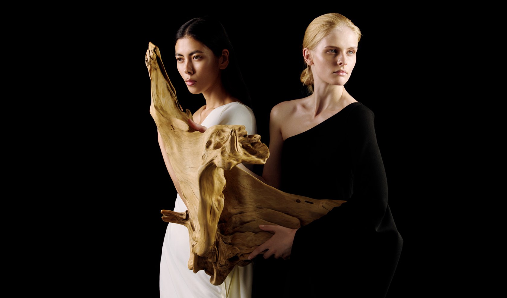 MIOGI LI — two models holding driftwood against black