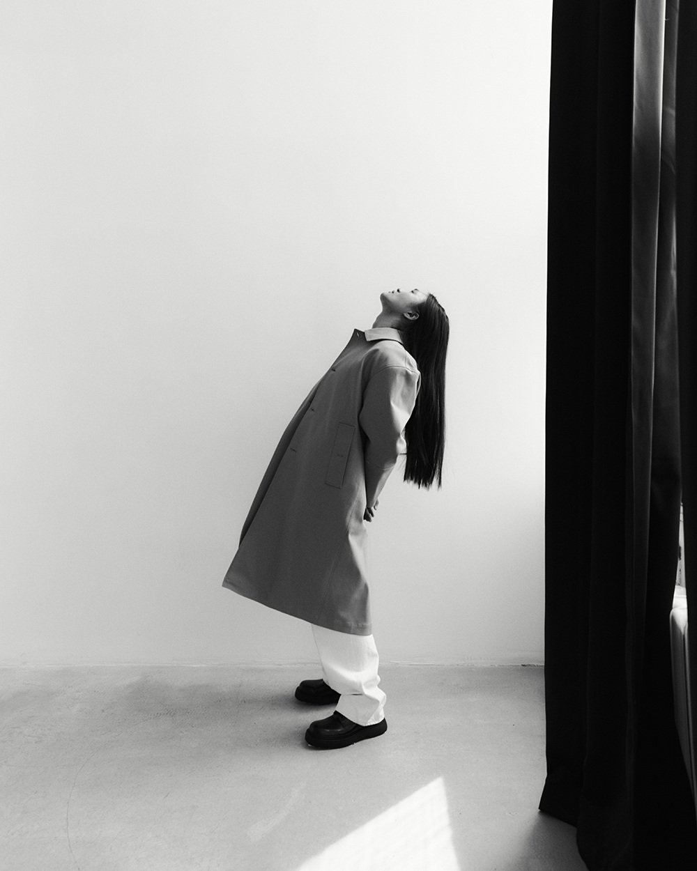 Private portrait — figure in a coat leaning back toward the light