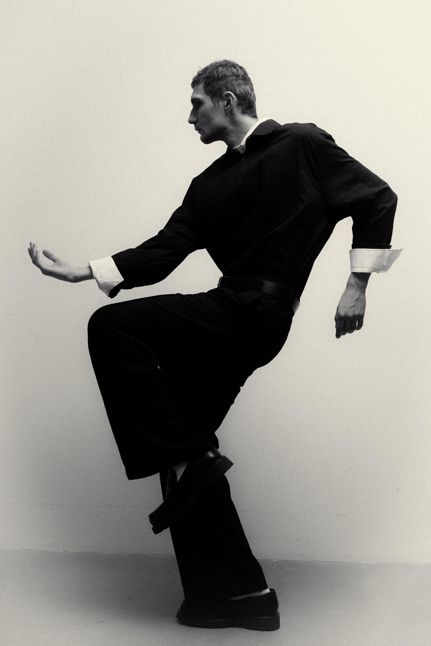 Nikita Orlov in movement, black look against a pale wall