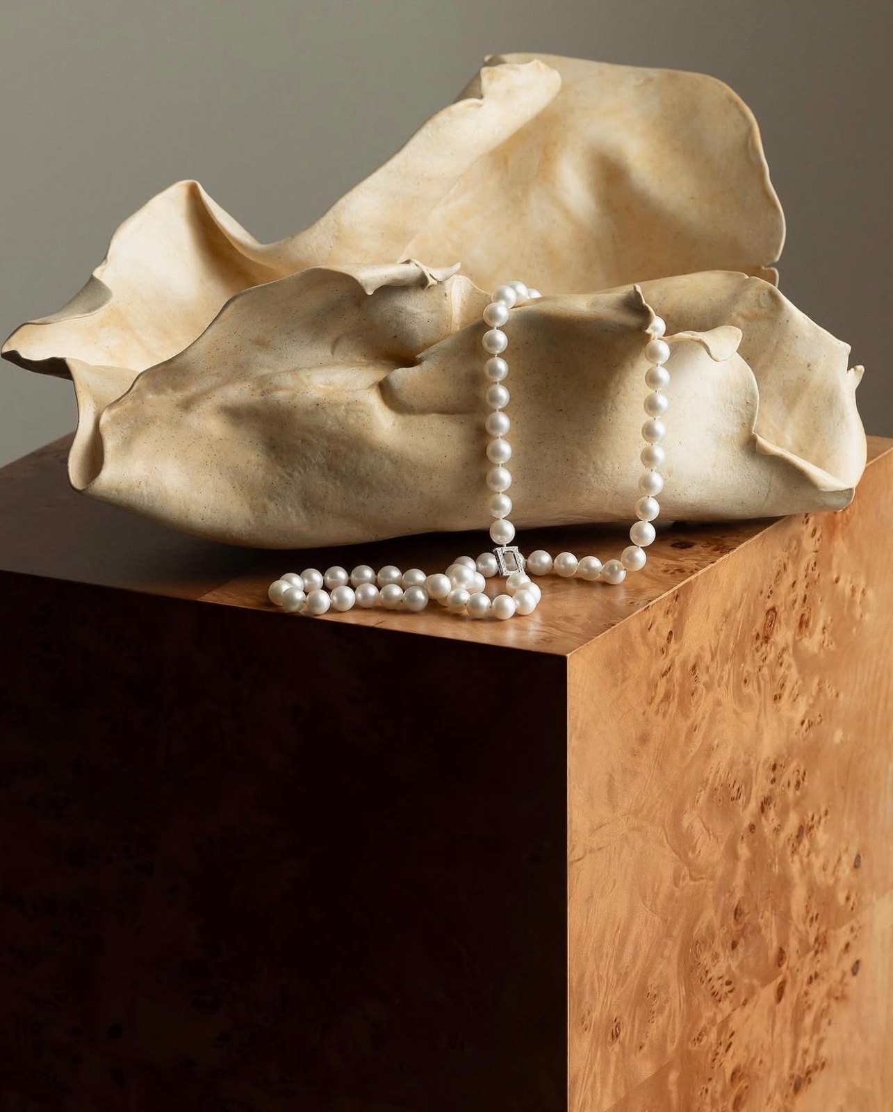 Still life — pearl necklace on a burr-wood plinth with ceramic form
