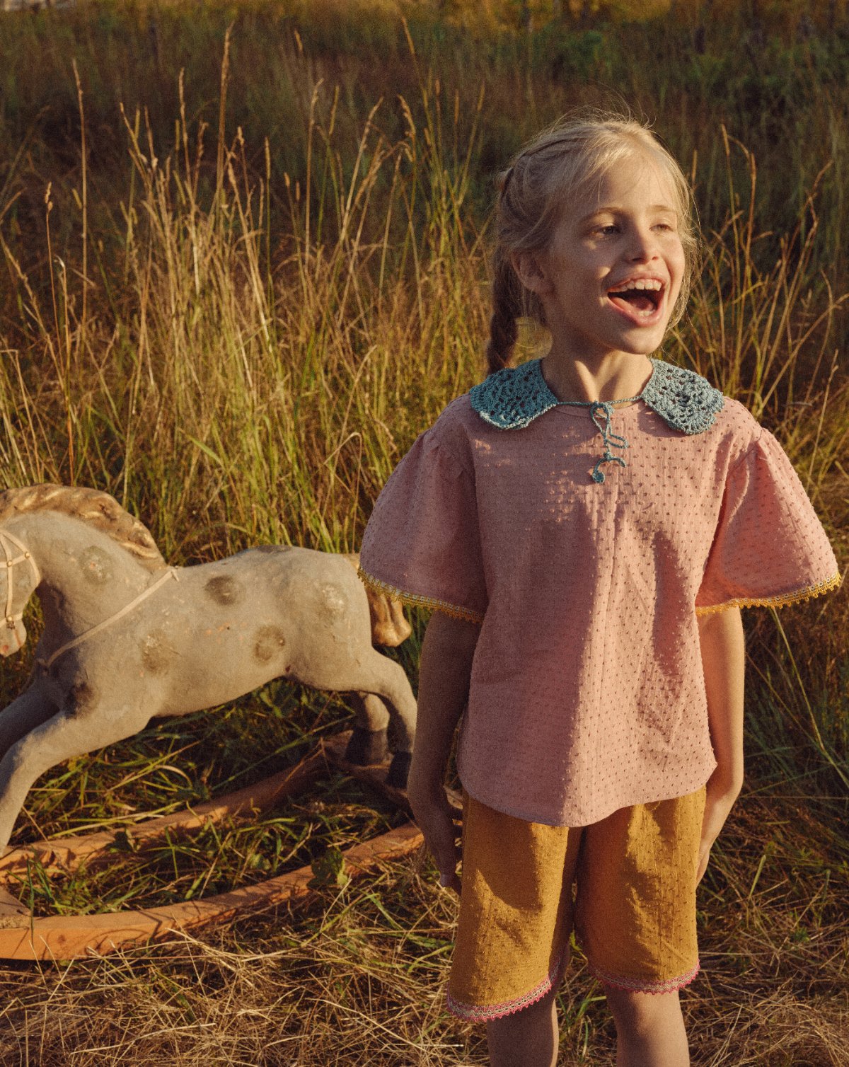 POLUSHA — campaign, girl in a pink blouse beside a wooden rocking horse