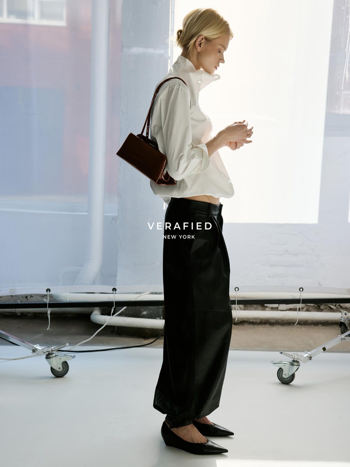 VERAFIED New York — white shirt and black leather trousers with a burgundy shoulder bag